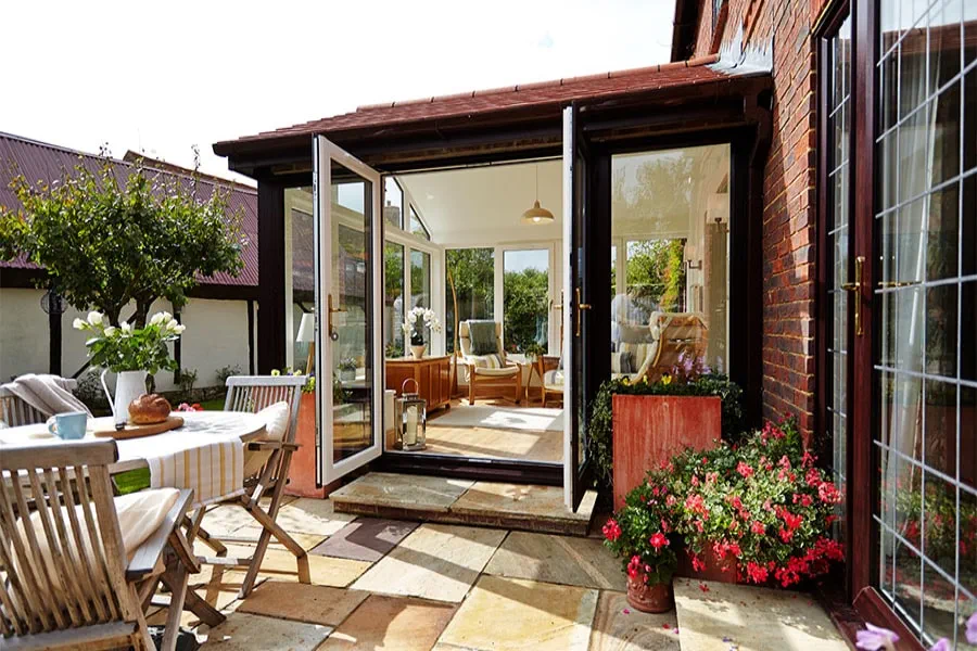 Solid roof conservatory with red tiles and dual Dark Woodgrain and White uPVC casement windows and French doors opening onto patio