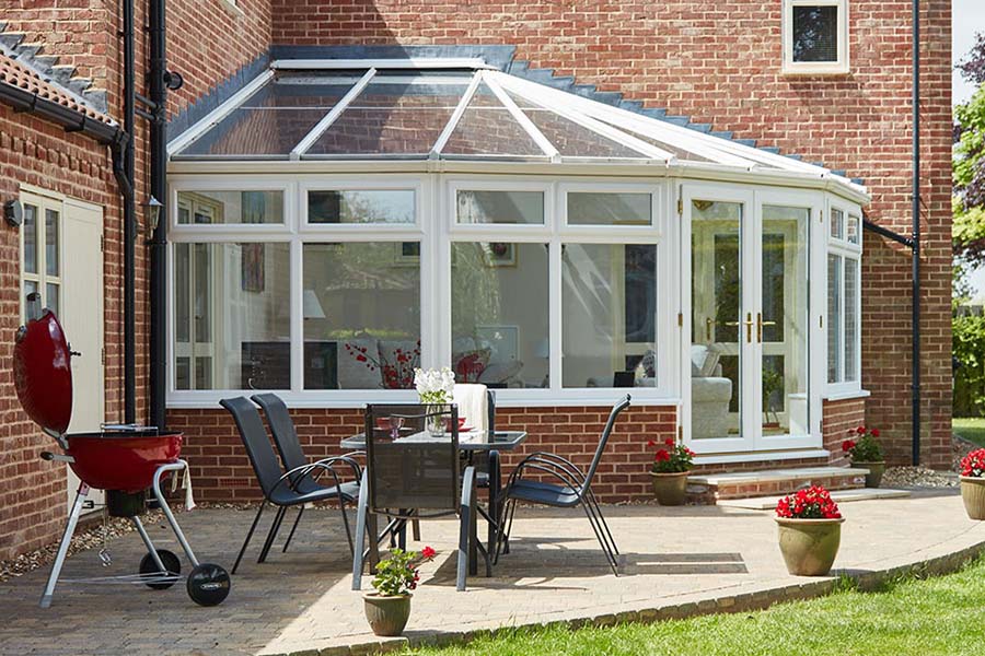 White woodgrain Victorian lean to UPVC conservatory with French doors on modern home from the Anglian conservatory range