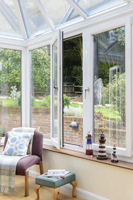 White tilt and turn casement window opening onto garden from conservatory from the Anglian tilt and turn window range