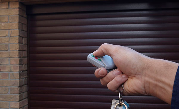 Operating a brown electric aluminium roller garage door with remote control from Anglian Home Improvements