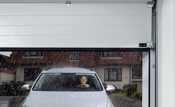 Car driving out of the rain into a steel sectional garage door from Anglian Home Improvements