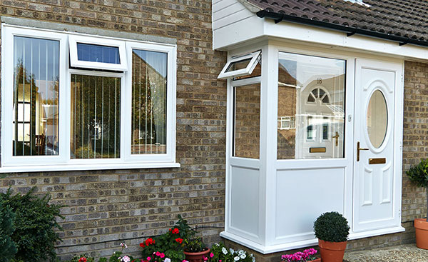 White UPVC porch and traditional front door with shaped window