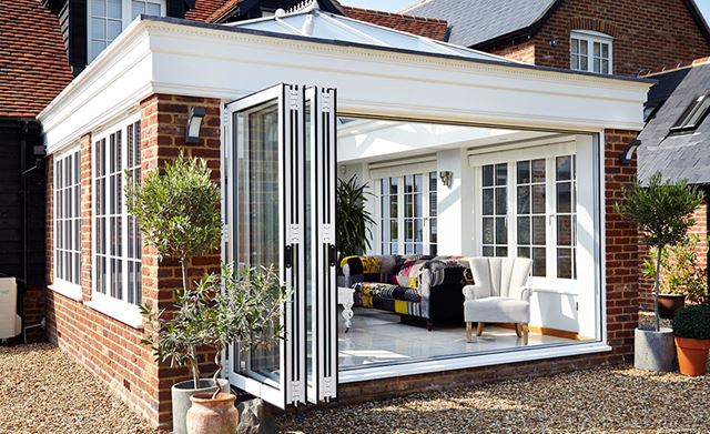 Side view of open White aluminium bifold doors on orangery from the Anglian bifold door range