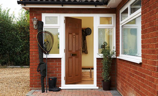 Golden Oak traditional composite front door with uPVC casement side panels and fishing equipment outside