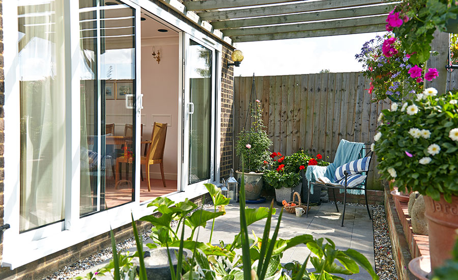 Aluminium sliding patio doors in white with white door handles with view of garden patio with wooden pergola