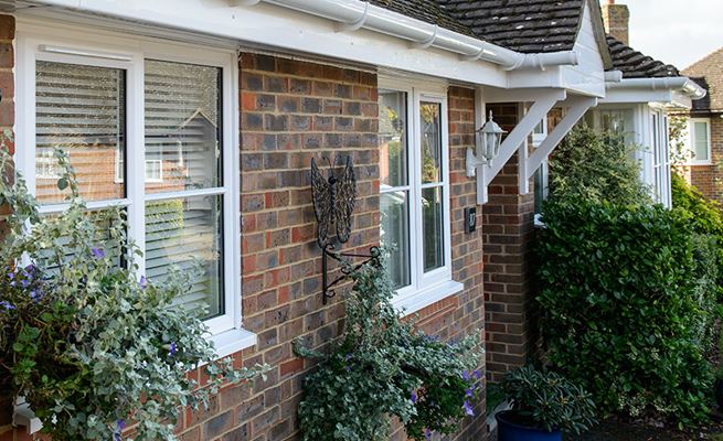White UPVC casement windows with cottage bars and roofline guttering and fascias on bungalow from Anglian Home Improvements