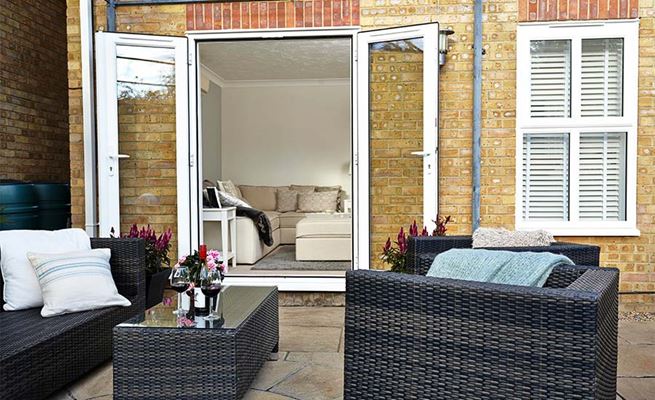 White lounge uPVC French doors with white handles opening onto garden patio from the Anglian French door range