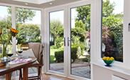 Dual white and anthracite grey uPVC French doors with chrome handles in dining room looking out on garden