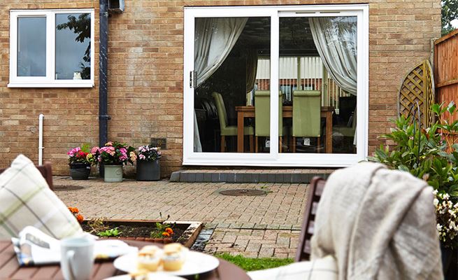 White uPVC sliding patio doors with top vent and large glazed panels leading onto brick weave patio from the Anglian patio doors range