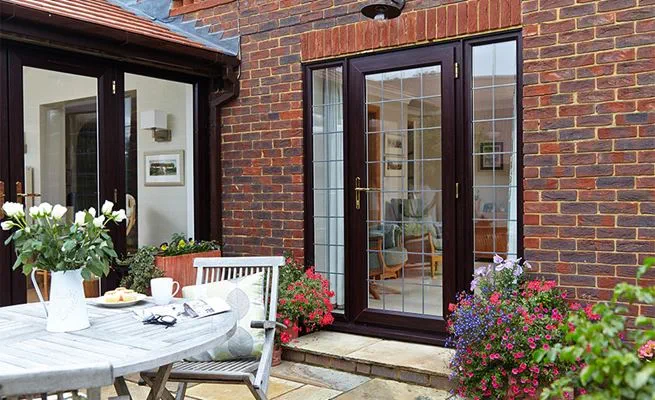 Dark brown woodgrain uPVC back door with leaded glass and conservatory with French doors from Anglian Home Improvements