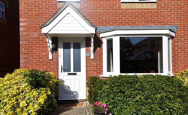 White UPVC bay window with side hung casement windows and White UPVC traditional front door from Anglian Home Improvements