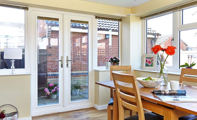 Pair of UPVC French doors and side casement windows in White with chrome handles in dining room extension