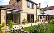 Dark woodgrain uPVC patio doors with gold handles and Victorian conservatory garden patio view