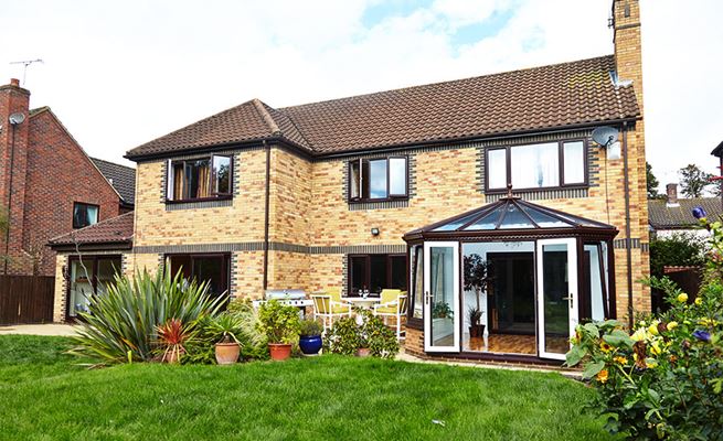 Dual dark brown and white UPVC casement windows patio doors and conservatory with French doors and tilt and turn windows