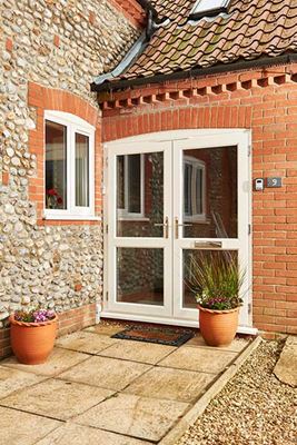 Cream uPVC French front doors with clear fully glazed glass chrome handle and letterbox exterior view from the Anglian French door range