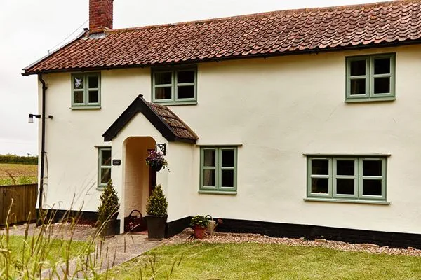 Dual Sage Green and White UPVC casement windows on a rendered cottage home from the Anglian windows range