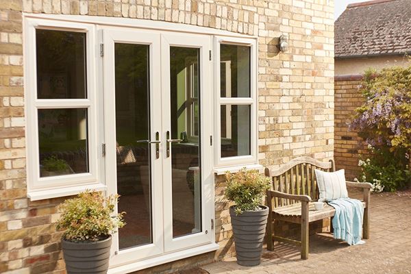 Cream uPVC French doors with side uPVC casement windows exterior view with wooden bench and blanket