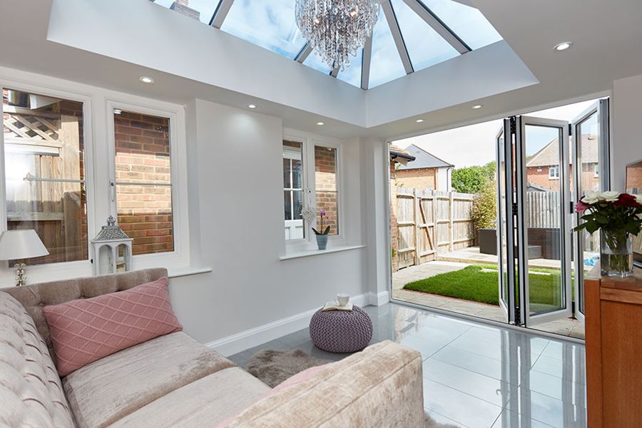 Internal view of small brick orangery with roof lantern and white aluminium bifold doors from the Anglian orangery range