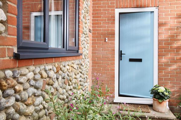 Duck Egg Blue composite door in cottage style with anthracite grey uPVC casement windows on cobbled house