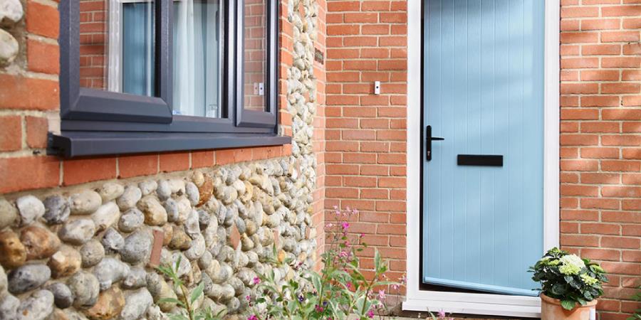 Duck Egg Blue composite door in cottage style with anthracite grey uPVC casement windows on cobbled house