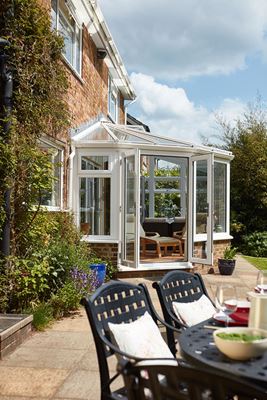 White UPVC lean to Victorian conservatory with French doors opening onto the patio from the Anglian conservatories range