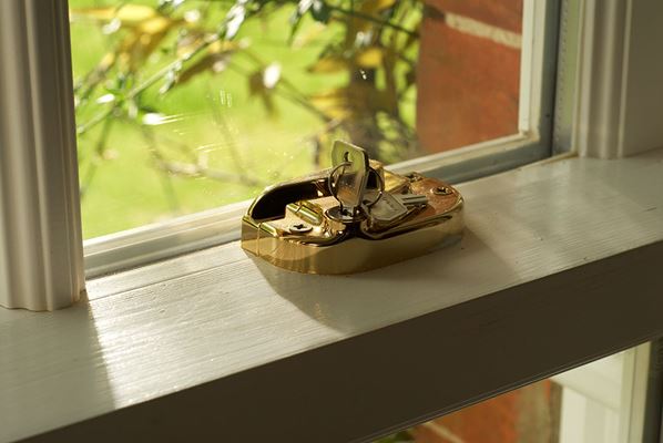 Close up of gold window lock on a White timber sash window from Anglian Home Improvements