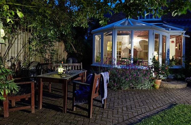 Night shot of White UPVC Victorian lean to conservatory and patio from the Anglian conservatories range