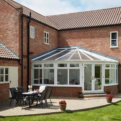 White woodgrain Victorian uPVC conservatory with French doors finished with gold handles on modern family home
