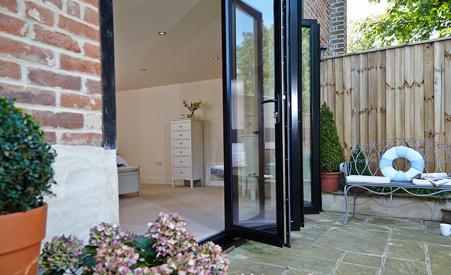 Side view of five panel aluminium bifold doors in Jet Black on ground floor bedroom from the Anglian bi-fold doors range