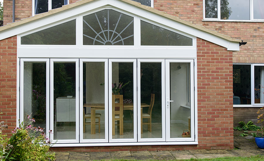 Six panel White aluminium bi-fold doors with shaped decorative windows on a rear house brick extension
