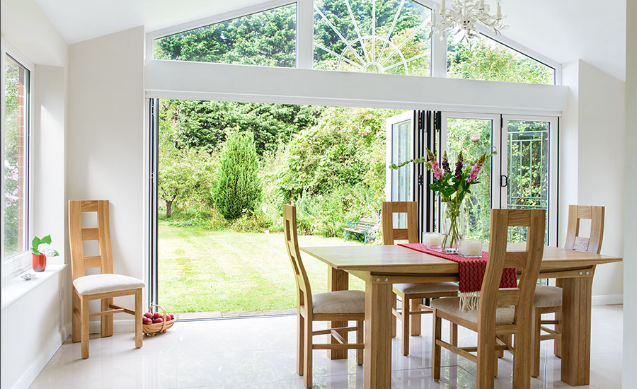 Open white aluminium bifold doors on extension with shaped windows from the Anglian bifold door range