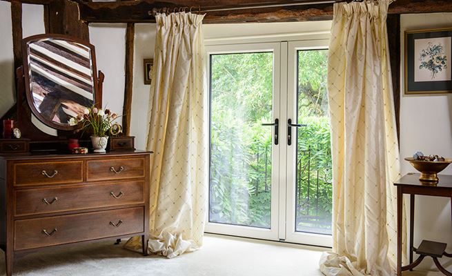 Dual coloured White and Anthracite Grey aluminium French doors with black handles on barn conversion bedroom balcony