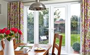 Pair of white uPVC French doors opening onto garden patio with candles and plants on the doorstep