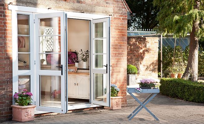 Cream uPVC French doors with black handles and casement windows with cottage bars