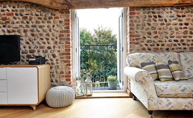Pair of open White uPVC French doors balcony interior view of cobblestone barn conversion with wooden beams