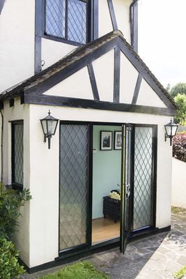 Black aluminium Victorian front door with decorative leaded bars on a traditional rendered cottage home from the Anglian front door range