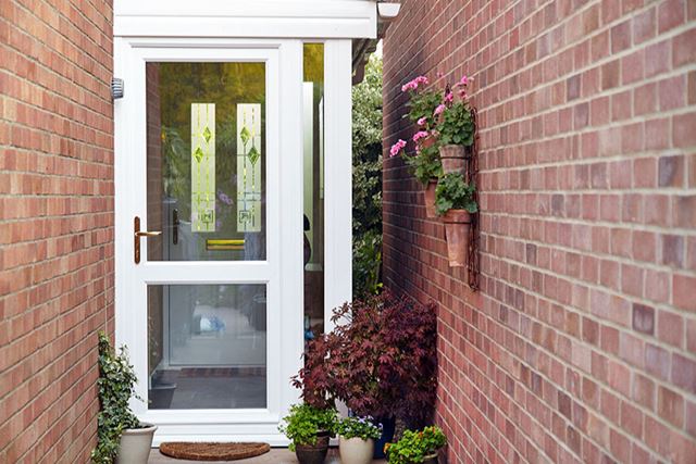 White uPVC double glazed back door with clear glass and gold handle in brick alleyway from the Anglian back doors range