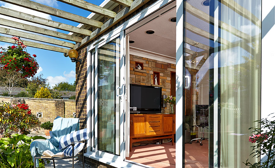 White aluminium patio doors with white handles sliding open to outside patio with timber pergola