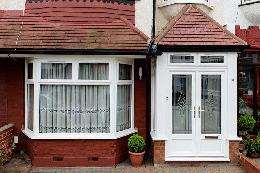 Ground floor view of White UPVC French door front porch and bay casement window from Anglian Home Improvements