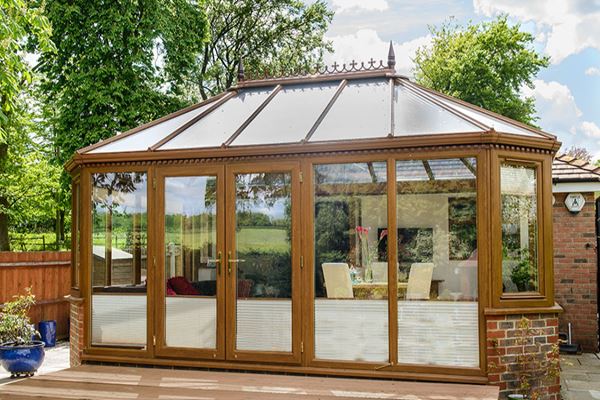 Brown Golden Oak Edwardian style UPVC conservatory with classic finials and large matching casement windows