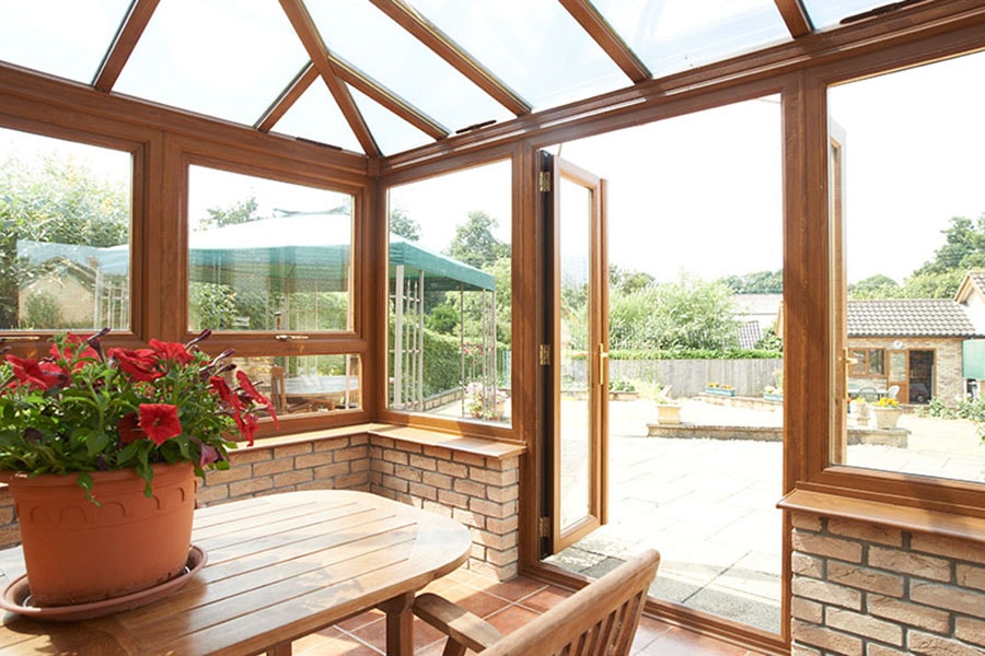 UPVC conservatory finished in Golden Oak with glass roof and large top hung casement windows and French doors