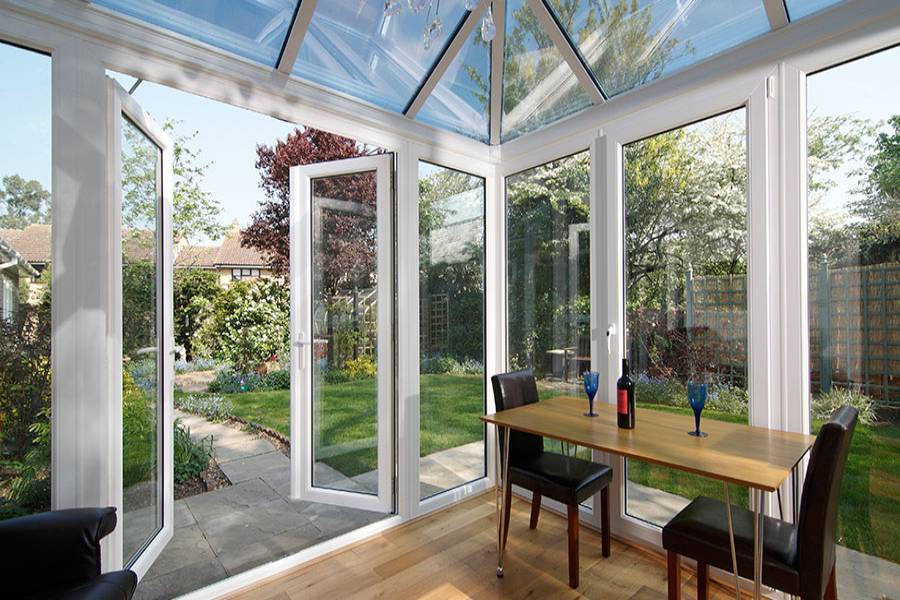 UPVC glass roof conservatory finished in White with large casement windows and French doors opening onto garden