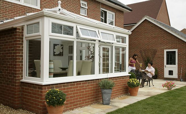White UPVC Elizabethan conservatory with brick side and Georgian window bars and French doors from Anglian Home Improvements