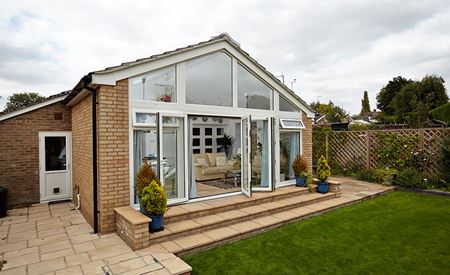 Buff brick contemporary gable end extension with white aluminium bi-fold doors and top hung casement windows