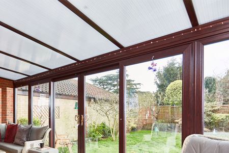 Dark woodgrain uPVC garden room with polycarbonate roof