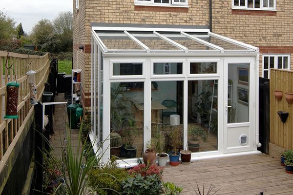 White Woodgrain UPVC lean to conservatory with single half glazed back door and catflap from the Anglian conservatories range