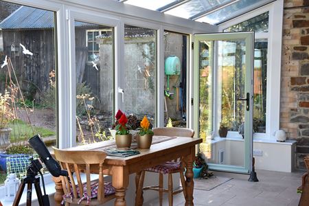 Dual sage green L shaped conservatory with uPVC French doors in open position