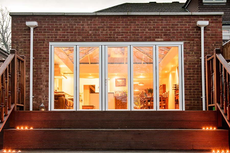 Anglian Home Improvements orangery at night with bifold doors and exterior decking