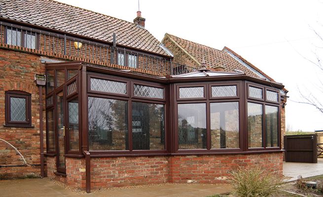 Dark woodgrain UPVC p-shaped conservatory with lean to roof and windows with leaded bars from Anglian Home Improvements