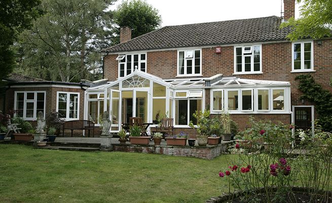 T-shaped conservatory in White UPVC with top hung and side hung casement windows and classic finials from the Anglian conservatory range